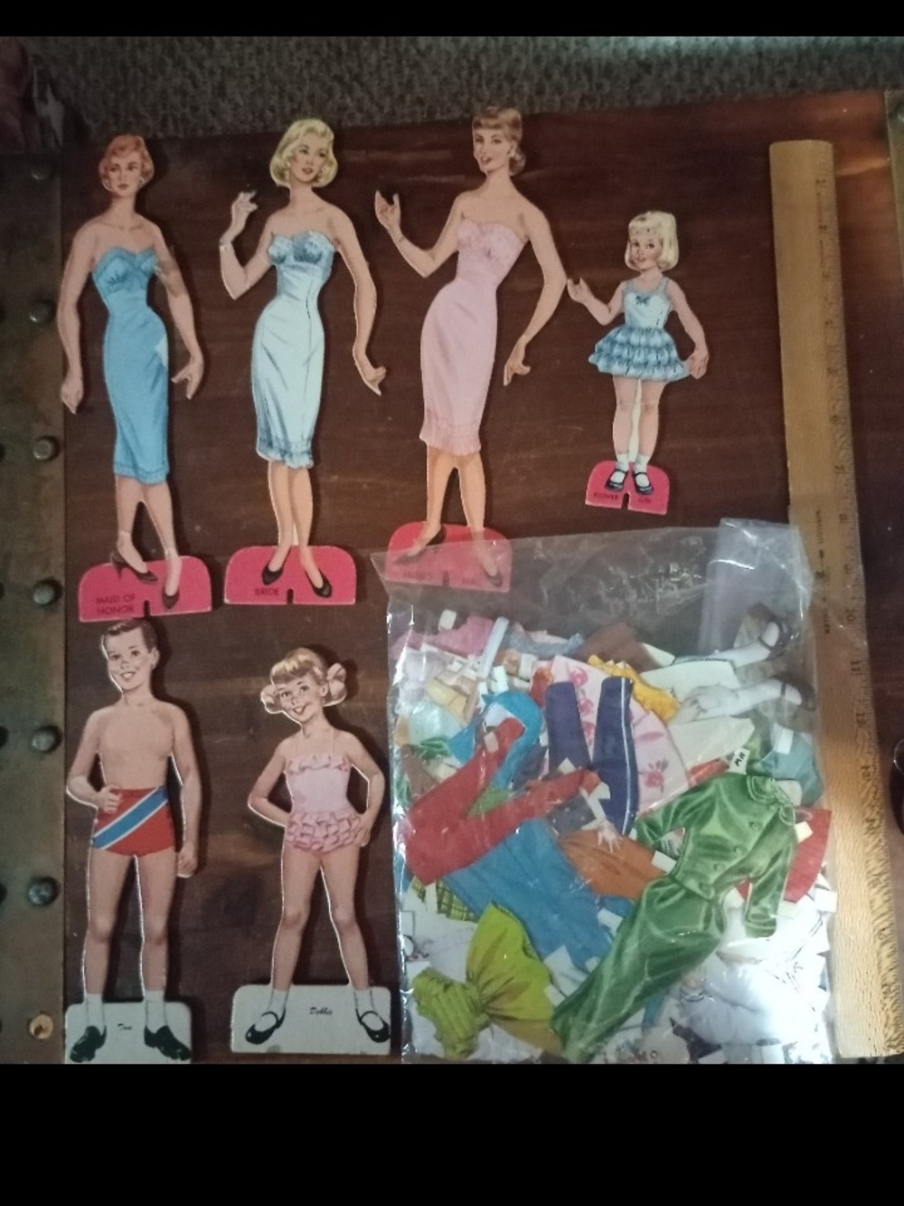 Six vintage paper dolls with bag of cut out paper doll clothes.